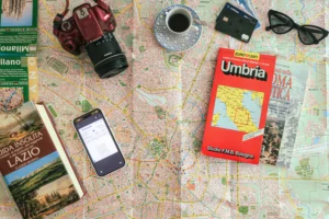 Fotografia de topo para planear uma viagem a Itália: mapa da cidade de Milão, mapa rodoviário da Úmbria, um cartão de embarque, uma câmara e guias de viagem